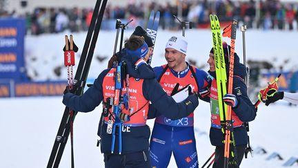 Les Français Eric Perrot, Fabien Claude et Quentin Fillon Maillet entourent Emilien Jacquelin après le relais d'Hochfilzen, le 15 décembre 2024. (KERSTIN JOENSSON / AFP)