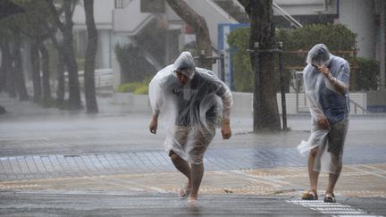 Des habitants de Naha, sur l'&icirc;le d'Okinawa (Japon) tentent d'&eacute;viter la pluie et les vents violents du typhon Vongfong, le 11 octobre&nbsp;2014. (KYODO / REUTERS )