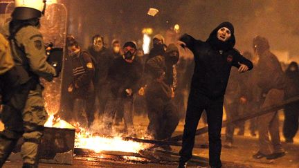 Un manifestant jette une pierre sur des policiers lors d'affrontements &agrave; Ath&egrave;nes (Gr&egrave;ce), le 12 f&eacute;vrier 2012. (YANNIS BEHRAKIS / REUTERS)