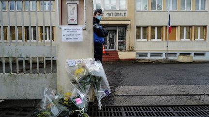 Un gendarme se tient près de fleurs posées devant l'entrée de la gendarmerie d'Ambert&nbsp;(Puy-de-Dôme), le 23 décembre 2020. (OLIVIER CHASSIGNOLE / AFP)