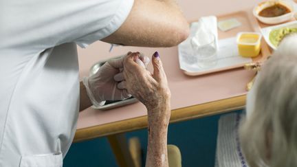 Une infirmière aide une patiente à prendre son repas à l'hôpital. (FRED DUFOUR / AFP)