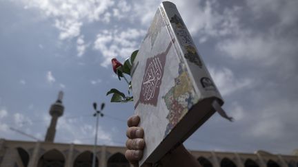 Un Iranien brandit un Coran, lors d'une manifestation contre l'autodafé d'un Coran en Suède, le 21 juillet 2023, à Téhéran (Iran). (MORTEZA NIKOUBAZL / NURPHOTO / AFP)