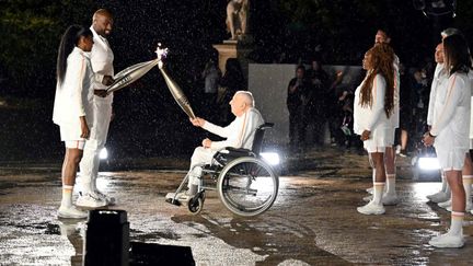 L'ancien cycliste Charles Coste, également le plus vieux médaillé olympique français, tend le flambeau à Teddy Rinner et à Marie-José Pérec, le 26 juillet 2024. (MOHD RASFAN / AFP)