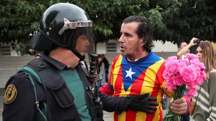 Un&nbsp;partisan du référendum d'indépendance en Catalogne face à un policier espagnol, le 1er octobre 2017 à Barcelone.&nbsp; (ALBERT GEA / REUTERS)