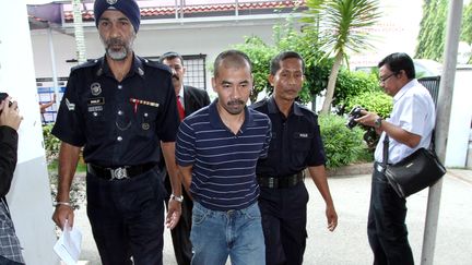 Un policier malaisien escorte Asni Omar, accus&eacute; du meurtre d'une touriste fran&ccedil;aise, le 17 mai 2012 &agrave;&nbsp;Kuantan (Malaisie). ( AFP )