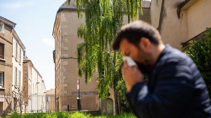 Un homme se mouche dans une rue à Poitiers, le 2 mai 2022. (MATHIEU HERDUIN / MAXPPP)