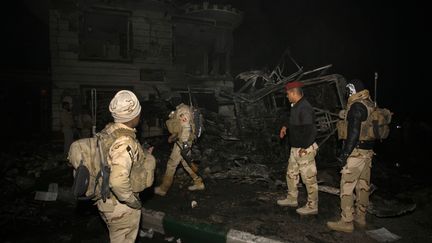 Les autorités irakiennes inspectent la carcasse du véhicule piégé qui a explosé dans une station-service en faisant au moins 70 morts, non loin de Bagdad, le 24 novembre 2016. (HAIDAR HAMDANI / AFP)