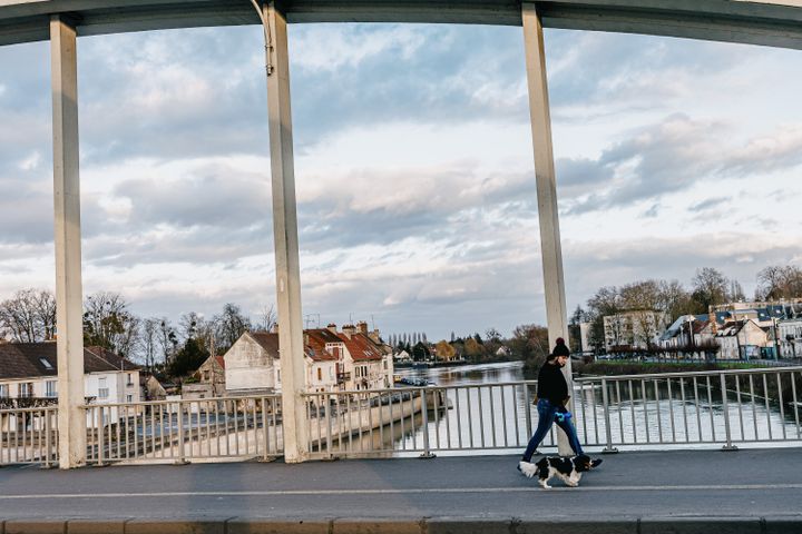 Une femme promène son chien au-dessus de l'Oise sur le pont qui relie les deux rives de Pont-Sainte-Maxence, le 31 janvier 2022. (PIERRE MOREL / FRANCEINFO)