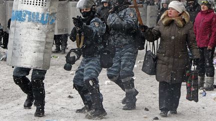 Une femme brandit un crucifix devant des policiers lors d'affrontements avec des manifestants &agrave; Kiev (Ukraine), le 22 janvier 2014. (GLEB GARANICH / REUTERS)