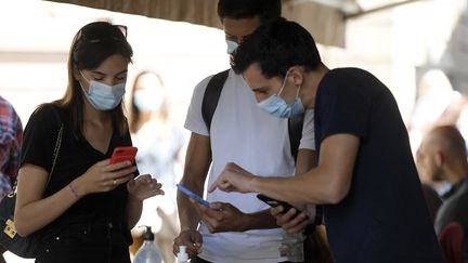 Un restaurateur contrôle les pass sanitaires de clients, le 9 août 2021. (FREDERICK FLORIN / AFP)