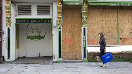 Une irlandaise passe devant un bar fermé à Dublin, le 21 octobre 2020. Depuis cette date un confinement national a été mis en place dans le pays contre la propagation du Covid-19. (PAUL FAITH / AFP)