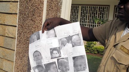 Un gardien montre les portraits des sept Fran&ccedil;ais enlev&eacute;s au Cameroun et qui se trouveraient au Nigeria, le 21 f&eacute;vrier 2013, &agrave; Yaound&eacute;. (REINNIER KAZE / AFP)