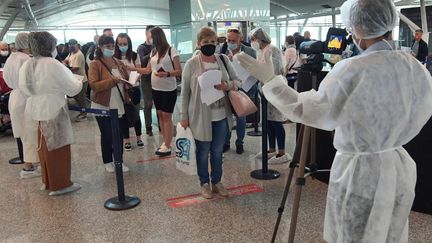 Des agents de santé tunisiens contrôlent les touristes européens à leur arrivée à l'aéroport international d'Enfidha-Hammamet, près de la ville méditerranéenne de Sousse, le 22 mai 2021. (FETHI BELAID / AFP)