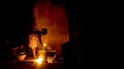 Près de 11.000 personnes vivent sans accès à l’électricité. Pour les villageois, il s’agit d’un des plus grands problèmes auxquels ils doivent faire face quotidiennement. Au retour des champs, le travail continue. Madame Tokinde prépare l’huile de palme dans sa phase finale. Elle ne s’éclaire qu’à l’aide d’une lampe artisanale à pétrole. (Pascal Maitre/Cosmos)