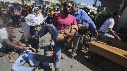 Un Palestinien porte un enfant bless&eacute;, apr&egrave;s le bombardement d'une &eacute;cole de l'ONU &agrave; Rafah, dans le sud de la bande de gaza, le 3 ao&ucirc;t 2014. ( IBRAHEEM ABU MUSTAFA / REUTERS)