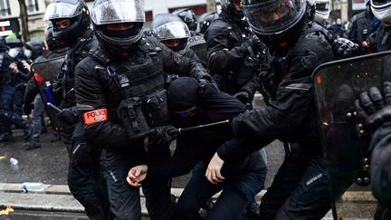 Un manifestant est tenu par deux policiers lors de la manifestation contre la proposition de loi "Sécurité globale", à Paris, le 12 décembre 2020. (MARTIN BUREAU / AFP)