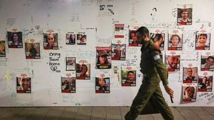 Un soldat israélien passe devant des portraits d'otages capturés par le mouvement islamiste Hamas, le 16 novembre 2023 à Tel-Aviv (Israël). (AHMAD GHARABLI / AFP)