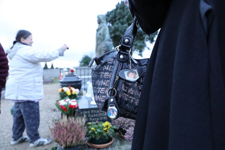 Anne devant la tombe de Claude François, à Dannemois (Essonne), le 1er février 2018. Au premier plan, des porte-clés à l'effigie de la star réalisés par ses fans.&nbsp; (SIMON GOURMELLET / FRANCEINFO)