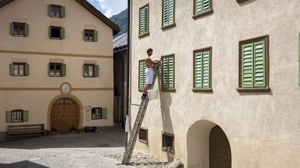 Un homme peint les volets d'un immeuble. (TIM GRAHAM / GETTY IMAGES EUROPE)