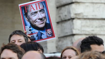 Un homme brandit une parodie de la une de Time Magazine consacr&eacute;e &agrave; Silvio Berlusconi, le pr&eacute;sident du Conseil italien avant que celui-ci ne pr&eacute;sente sa d&eacute;mission, Rome (Italie), le 12 novembre 2011. (GABRIEL BOUYS / AFP)