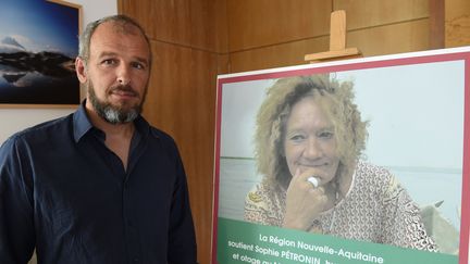 Sébastien Chadaud-Pétronin, fils de Sophie Pétronin, à Bordeaux (Gironde) le 29 août 2018, devant une photo de sa mère, otage au Mali. (MEHDI FEDOUACH / AFP)