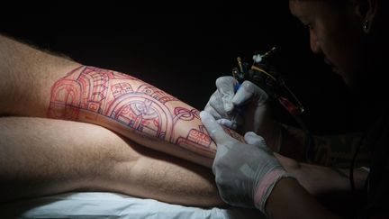 Un tatoueur pratique son art sur le corps d'un patient, le 3 avril 2016 à Papeete. (GREGORY BOISSY / AFP)