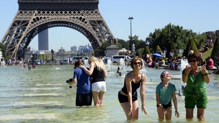 Des Parisiens se rafraichissent dans une fontaine du Trocadéro, devant la Tour Eiffel, à Paris, en juillet 2016 (BERTRAND GUAY / AFP)