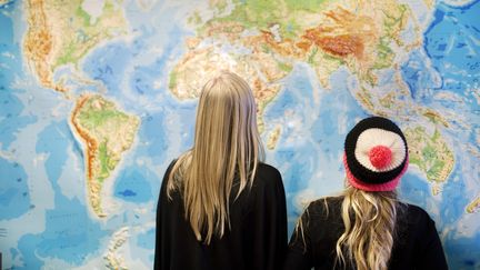 Deux &eacute;l&egrave;ves devant une carte du monde, dans une salle de classe. (JOHANNA HANNO / BILDHUSET / AFP)