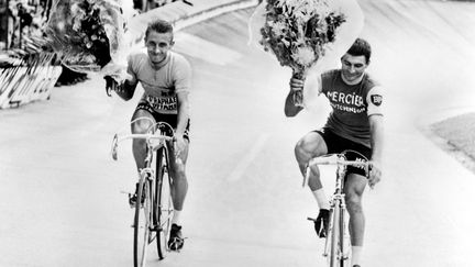 Jacques Anquetil, vainqueur du Tour de France 1964, et son dauphin, Raymond Poulidor (à dr.) effectuent un tour d'honneur sur le vélodrome du Parc des Princes, à Paris, le 14 juillet 1964. (STAFF / AFP)