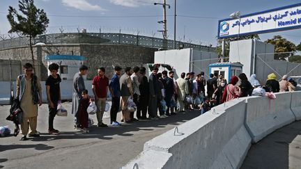 Des gens patientent devant une porte d'accès à l'aéroport de Kaboul (Afghanistan) dans l'espoir d'être évacués, le 28 août 2021. (WAKIL KOHSAR / AFP)