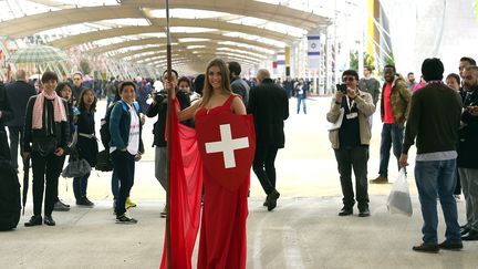 Au pavillon suisse, h&ocirc;tesse helv&eacute;tique en robe rouge et bouclier idem, &agrave; croix blanche, comme le drapeau du pays. (OLIVIER MORIN / AFP)