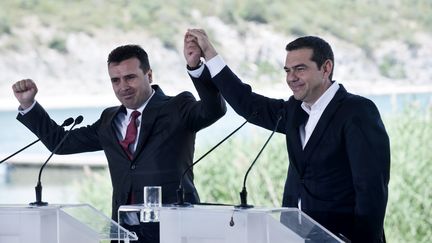 Les Premiers ministres grec et macédonien,&nbsp;Alexis Tsipras et&nbsp;Zoran Zaev, se réjouissent de la signature d'un accord pour changer le nom de la Macédoine, le 17 juin 2018 dans la région frontalière de Prepès. (SAKIS MITROLIDIS / AFP)