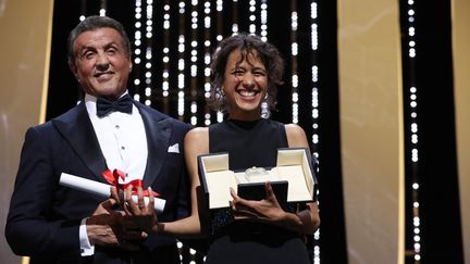 La réalisatrice Mati Diop reçoit, le 25 mai 2019 à Cannes, le Grand Prix des mains de Sylvester Stalone pour "Atlantique". (VALERY HACHE / AFP)