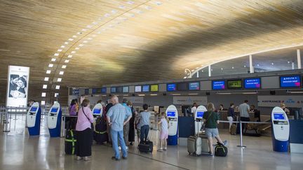 Des passagers attendent devant le comptoir d'Air France à l'aéroport de Roissy-Charles-de-Gaulle, le 27 juillet 2016. (MAXPPP)