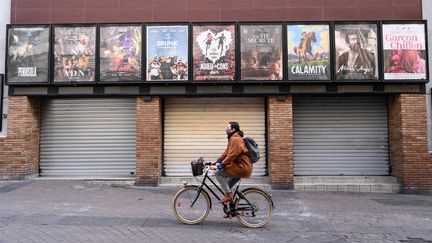 Une femme passe à vélo devant un cinéma fermé à Montpellier&nbsp;(Hérault), le 16 novembre 2020. (PASCAL GUYOT / AFP)