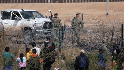 Des agents de la Garde nationale du Texas empêchent les migrants en provenance du Venezuela de franchir une clôture de barbelés après avoir traversé le Rio Grande depuis Ciudad Juarez, dans l'État de Chihuahua, au Mexique, le 29 février 2024. (HERIKA MARTINEZ / AFP)