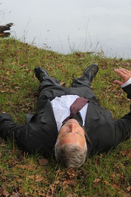 Un acteur reproduit la position du cadavre de Robert Boulin après avoir été sorti de l'eau, le 28 octobre 2019,&nbsp;sur les berges de l'étang Rompu (Yvelines). (CLEMENT PARROT / FRANCEINFO)