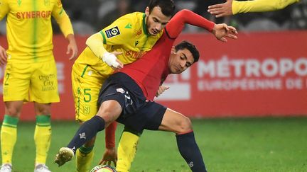 Le Lillois Benjamin André (en rouge) à la lutte avec le Nantais Pedro Chirivella lors de la 15e journée de Ligue 1 au stade Pierre-Mauroy, samedi 27 novembre. (FRANCOIS LO PRESTI / AFP)