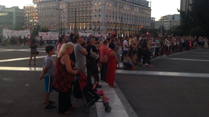 Des touristes assistent &agrave; la rel&egrave;ve de la garde, devant le Parlement &agrave; Ath&egrave;nes (Gr&egrave;ce), tandis que des Grecs manifestent, le 12 juillet 2015. (ARIANE NICOLAS / FRANCETV INFO)