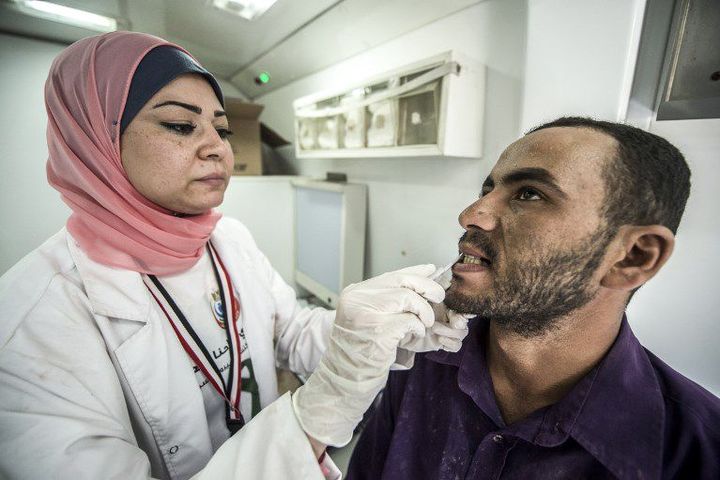 Une soignante examine un patient en Egypte le 3 août 2017, dans le cadre de la lutte contre l'hépatite C. (KHALED DESOUKI / AFP)