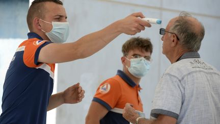 Un agent de la protection civile prend la température d'un homme à Laval (Mayenne), le 17 juillet 2020. (JEAN-FRANCOIS MONIER / AFP)