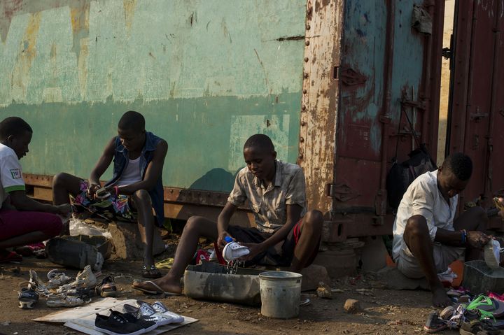 Des jeunes nettoient des chaussures usagées pour les revendre sur un marché à Bujumbura le 24 juillet 2015. (PHIL MOORE / AFP)