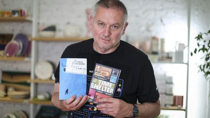 L'écrivain bulgare Georgi Gospodinov, lauréat de l'International Booker Prize 2023, pose pour une photo avec son livre "Time Shelter" à Sofia le 31 mai 2023. (DIMITAR KYOSEMARLIEV / AFP)