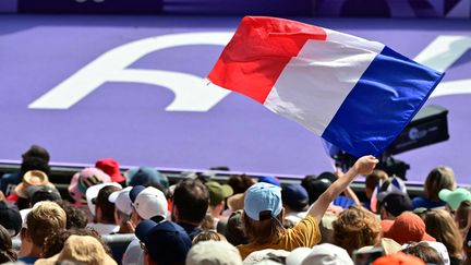 Un supporter tient un drapeau français au Stade de France à Saint-Denis pendant les Jeux olympiques, le 3 août 2024. (MARTIN  BERNETTI / AFP)