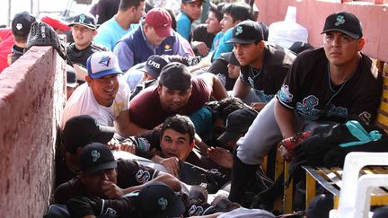 Des joueurs de baseball se prot&egrave;gent apr&egrave;s avoir entendu des coups de feu dans un stade &agrave; Saltillo (Mexique), le 13 mars 2012. (EPA / MAXPPP)