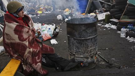 Un opposant au pr&eacute;sident Ianoukovitch se r&eacute;chauffe sur la place Ma&iuml;dan, &agrave; Kiev (Ukraine), samedi 22 f&eacute;vrier 2014. (BAZ RATNER / REUTERS)