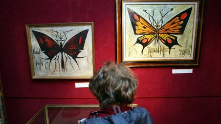 Une femme regarde un faux tableau du peintre Bernard Buffet (G) exposé à côté d'un vrai, le 11 janvier 2006 à Paris, dans le cadre de l'exposition qui doublait le colloque "Vrai ou Faux, les critères de l'authenticité dans le marché de l'art" organisé par la Confédération européenne des experts d'art (Cedea) à Drouot-Montaigne.&nbsp; (FRANCK FIFE / AFP)