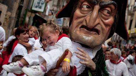 Le Kiliki Caravinagre porte un enfant lors du traditionnel d&eacute;fil&eacute; des f&ecirc;tes de San Fermin &agrave; Pampelone (Espagne), le 10 juillet 2012. (PABLO BLAZQUEZ DOMINGUEZ / GETTY IMAGES)