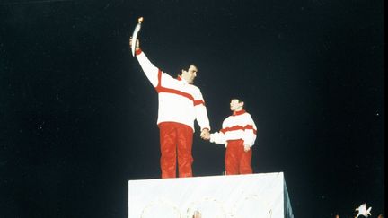 Michel Platini brandit la flamme olympique lors de la cérémonie d'ouverture des JO d'Albertville (Savoie), à côté du petit François-Cyrille Grange, le 8 février 1992. (BOCCON-GIBOD/SIPA / SIPA)