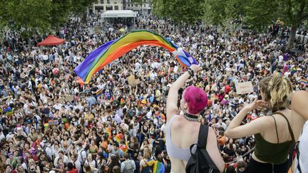 Deux personnes brandissent un drapeau arc-en-ciel lors de la Marche des fiertés de Paris le 26 juin 2021. (JACOPO LANDI / HANS LUCAS / AFP)